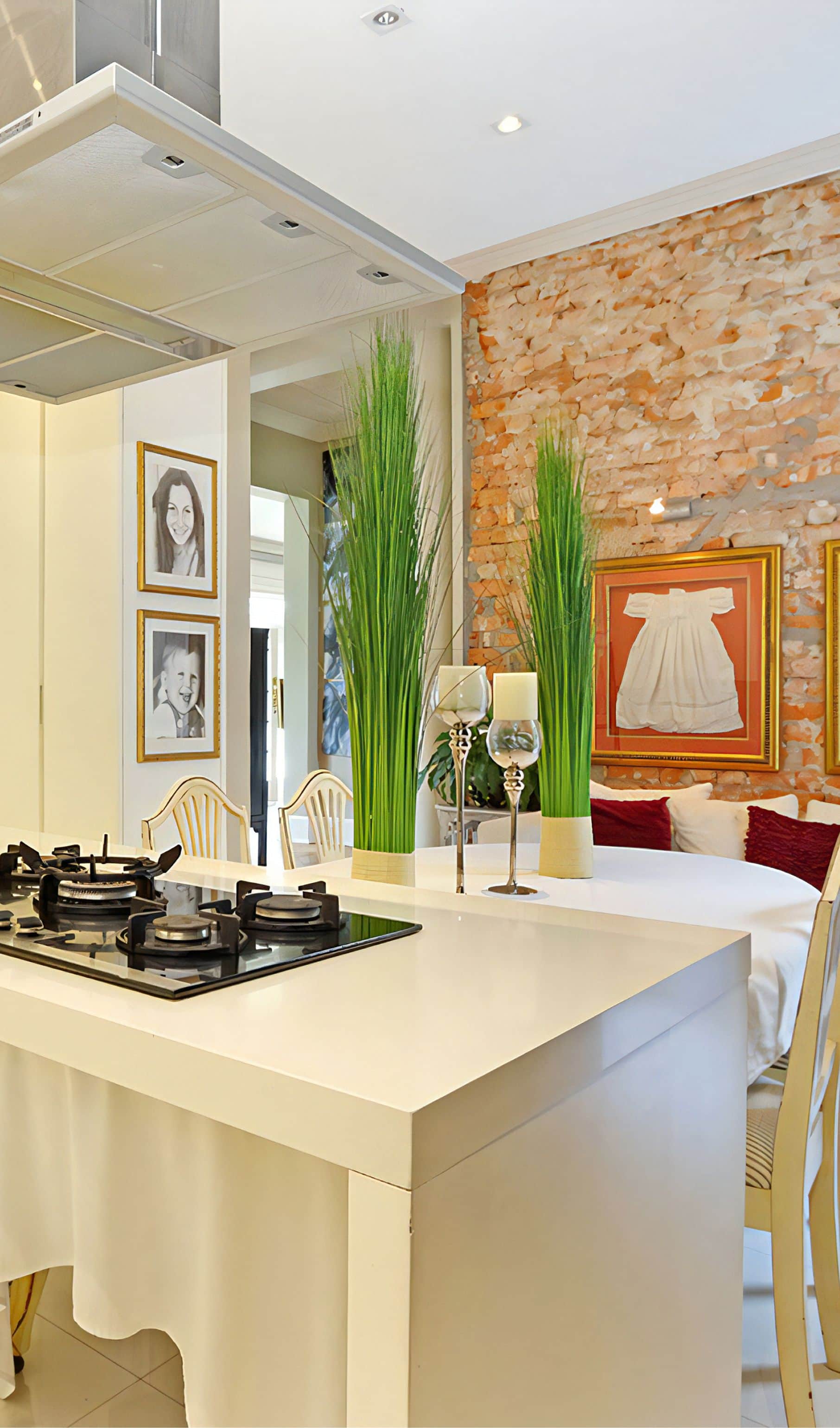 Kitchen island with a gas hob beside an exposed brick wall and a framed christening gown