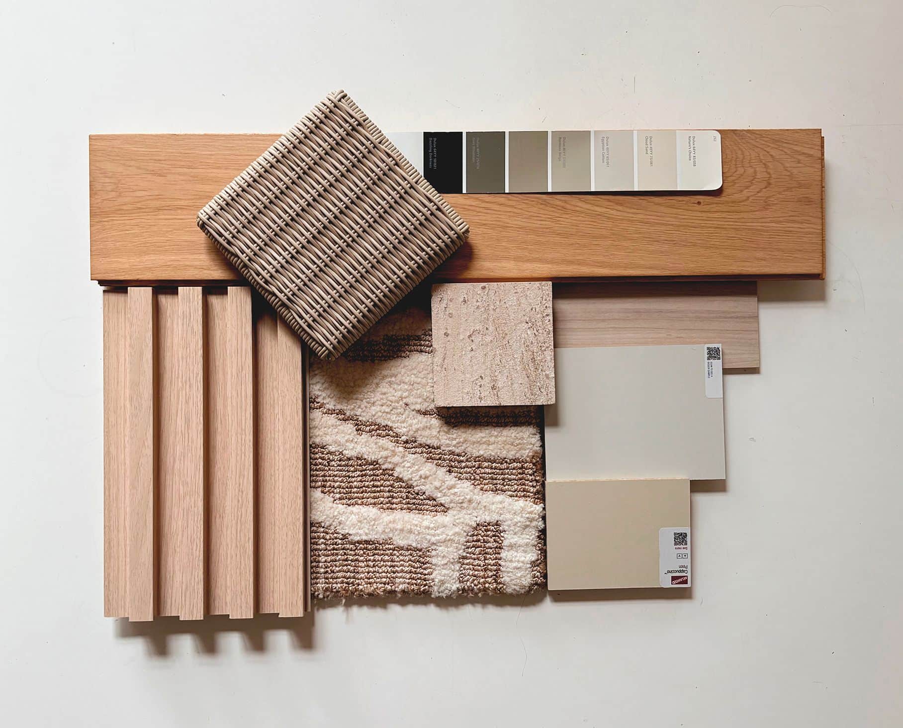 Material sample board with oak slats, woven fabric, travertine, a textured rug and paint swatches